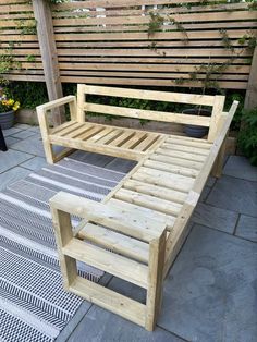 a wooden bench sitting on top of a patio next to a planter filled with flowers