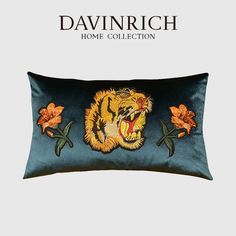 a blue pillow with an embroidered tiger on the front and side, along with orange flowers