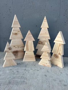 small wooden christmas trees lined up against a gray wall with one missing the top and another missing the bottom