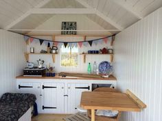 a small kitchen area with a table and chairs in it, next to a bed