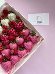 a pink box filled with lots of chocolate covered strawberries and raspberries in it