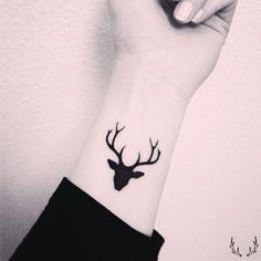 a woman's wrist tattoo with a deer head on the left side of her arm