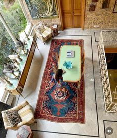 a woman sitting on top of a rug in a living room