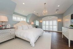 a bedroom with blue walls, white furniture and a chandelier hanging from the ceiling