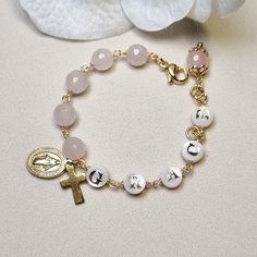 This stunning Baptism bracelet is a truly divine piece that combines elegance and spiritual significance. Crafted with natural rose quartz, it features gold plated Miraculous medal and cross charms that symbolize protection and faith. The bracelet is personalized with a handcrafted initial letter, adding a unique touch to this meaningful piece. Perfect for commemorating a special occasion or as a thoughtful gift, this bracelet is a beautiful reminder of faith and blessings. *MATCHING ROSARY PRAY Spiritual Pink Personalized Bracelets, Spiritual Personalized Pink Bracelets, Personalized Pink Spiritual Bracelets, Personalized Pink Spiritual Bracelet, Spiritual Personalized Pink Bracelet, Spiritual Rose Gold Rosary Bracelet Gift, Spiritual Name Bracelet For Mother's Day, Elegant Pink Bracelets For First Communion, Personalized Spiritual Bracelets For First Communion