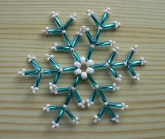 a snowflake made out of beads sitting on top of a wooden table