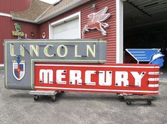 an old neon sign is sitting in front of a red building that says lincoln mercury