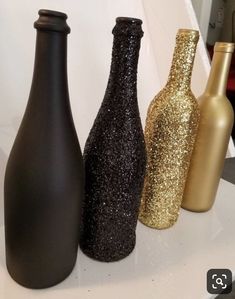 three black and gold vases sitting on top of a white shelf next to each other