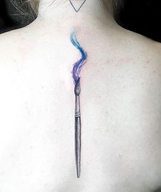 the back of a woman's neck with a blue and purple brush tattoo on it