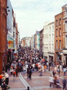 a crowd of people walking down a street next to tall buildings