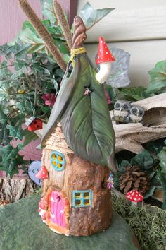 a small house made out of tree stumps with plants and mushrooms on the roof