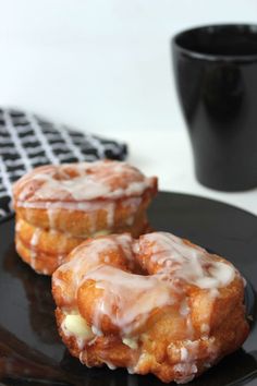 two glazed donuts sitting on top of a black plate