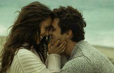 a man and woman embracing each other on the beach