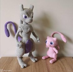 two crocheted stuffed animals sitting next to each other on top of a wooden table