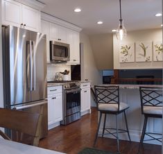 a kitchen with stainless steel appliances and white cabinetry, along with hardwood floorsing