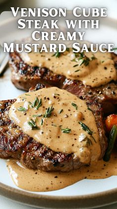 two steaks covered in gravy on top of a plate with carrots