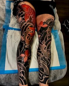 a person laying on top of a bed with lots of tattoos on their arms and legs