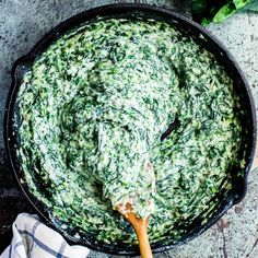 spinach dip in a cast iron skillet with a wooden spoon on the side