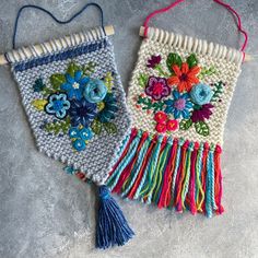 two handmade wall hangings with flowers and tassels on each one side