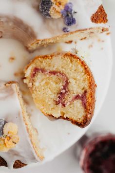 a piece of cake on a white plate with berries and icing next to it