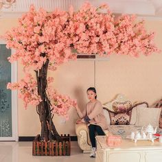 a woman sitting on a couch under a pink tree