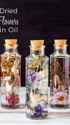 three glass bottles filled with dried flowers in oil