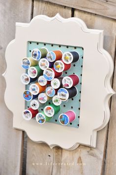 a white frame with some spools of thread in it on a wooden fence