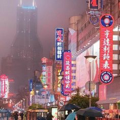 people with umbrellas are walking in the rain on a city street near tall buildings