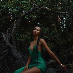 a woman in a green dress sitting on a tree branch