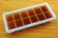 a plastic container filled with lots of ice cubes on top of a wooden table