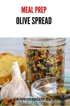 a jar filled with olives next to bread and garlic