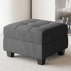 a gray ottoman sitting on top of a white rug