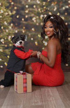 a woman in a red dress is holding a small dog and posing for a photo