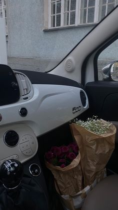 the interior of a car with flowers and paper bags in the passenger side door area