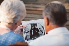 an older woman holding up a black and white photo with the image of two people