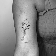 a black and white photo of a woman's arm with flowers in a vase