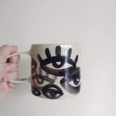 a hand holding a coffee mug with black and white designs on it's side