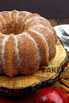 a bundt cake sitting on top of a wooden cutting board next to an apple