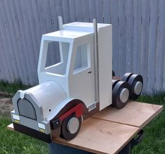 a toy truck is sitting on top of a wooden table in the grass next to a fence