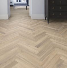 an empty room with wood flooring and white walls, along with a chest of drawers