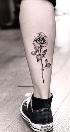 a black and white photo of a rose tattoo on the leg