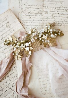 a hair comb with flowers and leaves on top of an old paper sheet, next to a piece of writing