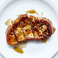 a piece of toasted bread on a white plate with syrup drizzled around it