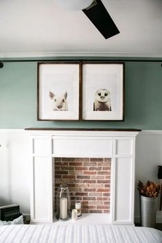 two framed pictures above a fireplace in a bedroom