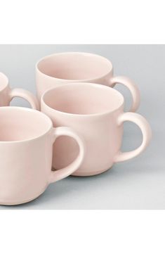 four pink coffee mugs sitting next to each other on a gray surface with one cup in the middle