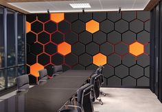 an empty conference room with black chairs and orange hexagonal panels on the wall