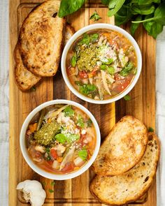 two bowls of soup on a cutting board with bread