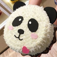 a panda bear cake with white frosting and pink hearts on it's face