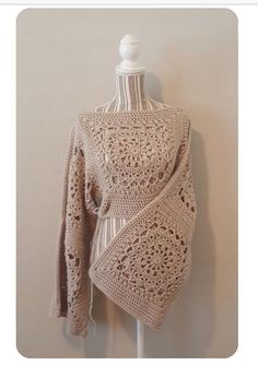 a crocheted sweater is hanging on a mannequin