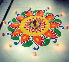 a colorful rangdi with candles on the ground in front of it and an oil lamp